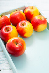 apples at blue tray, white wood table