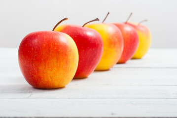apple fruits in a row, white wooden table background