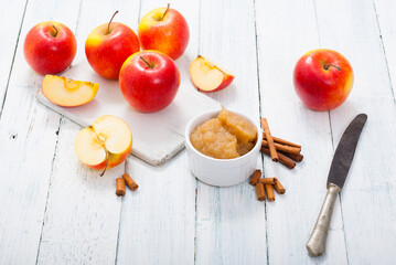 apple jam at porcelain dish, apples, cinnamon, white wood table background
