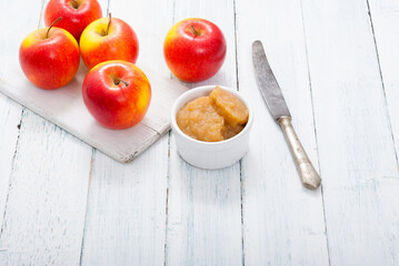 apple jam at porcelain dish, apples, cinnamon, white wood table background