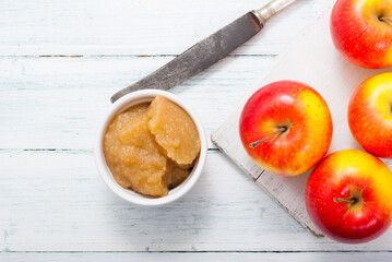 apple jam at porcelain dish, apples, cinnamon, white wood table background