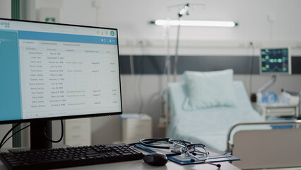 Close up of desk with computer and medical tools in empty hospital ward. Nobody in space with bed...