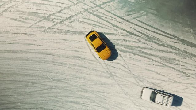 yellow ford mustang drifting one ice from a drone perspective