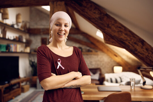Young confident woman with breast cancer standing with arms crossed and looking at camera.