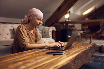 Woman with cancer surfing the net on laptop at home.