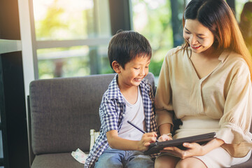 Mother and son with digital pencil using smart tablet for playing, learning preschool in digital age