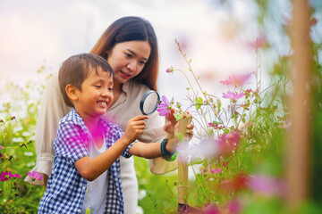 Mother and son with a magnifying glass exploring, learning with nature, insect, flower garden...