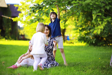 Obraz premium Young large family on a summer morning walk. Beautiful mother with children is playing in the park.
