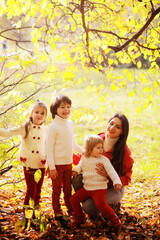 Fototapeta premium Young family on a walk in the autumn park on a sunny day. Happiness to be together.