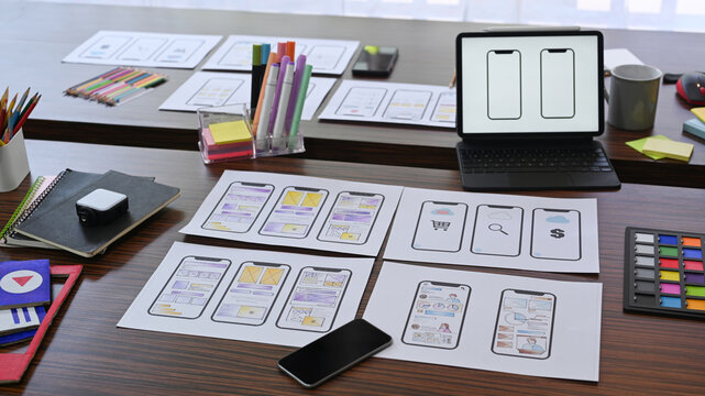 Designer working desk with wireframe sketches of screens for mobile application. User experience concept.