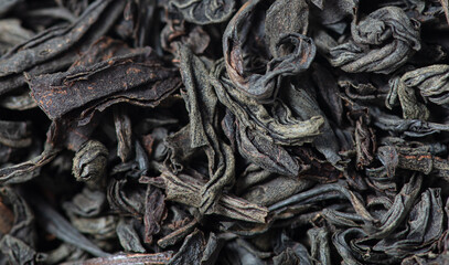 Dried black tea leaves as background.