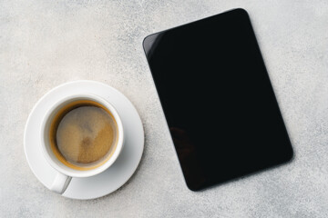Fototapeta na wymiar Digital tablet and coffee cup on gray table