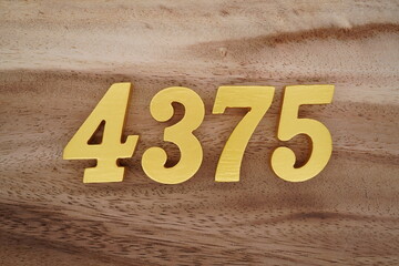 Golden Arabic numerals on a real brown and white wooden floor number 4375