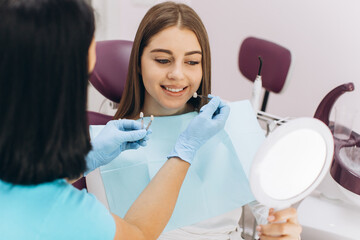 A female dentist helps her patient choose the color of the implant or crown using a color scale