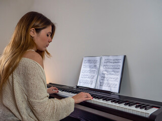 Student woman playing piano with music sheet
