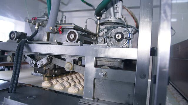 Complicated mechanism moving to produce marshmallow desserts. Automated line at manufacturing sweets.