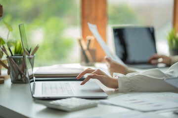 Woman sitting at desk and connecting with her laptop, she is working and typing on the keyboard, hands close up