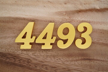 Golden Arabic numerals on a real brown and white wooden floor number 4493