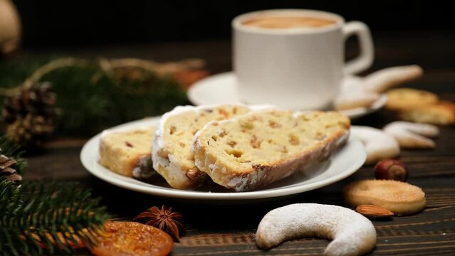 Sliced Traditional Christmas stollen cake with marzipan and New Year decorations on wooden background