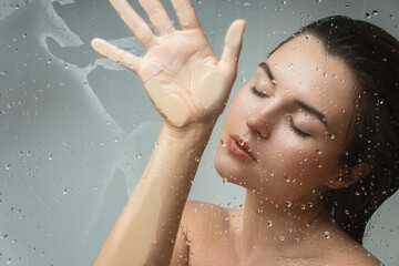 Portrait of sensual woman captured through wet glass
