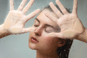 Portrait of sensual woman captured through wet glass