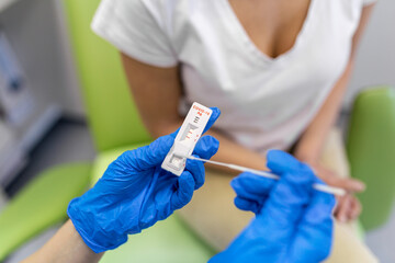 Doctor doing coronavirus rapid test at the hospital. Doctor laboratory assistant takes swab from nose of sick patient. Unrecognizable doctor with protective glove taking coronavirus rapid test