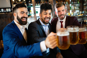 People, friendship and celebration concept. Happy business male friends drinking beer at pub