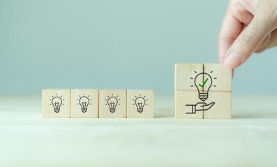 Suggestion and consulting concept. New idea, solution. Putting wooden cubes with light bulb on hand icon on beuatiful grey background and copy space. Business review, strategy suggestion for busines - obrazy, fototapety, plakaty