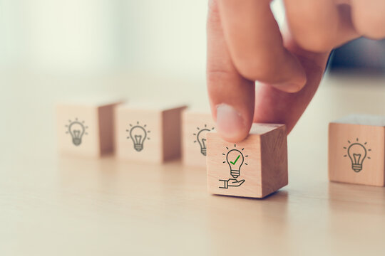 Suggestion and consulting concept. New idea, solution. Putting wooden cubes with light bulb on hand icon on beuatiful grey background and copy space. Business review, strategy suggestion for busines