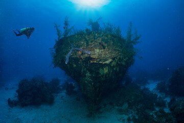 Fototapeta na wymiar A scuba diver explores a sunken shipwreck in The Bahamas, Long Island, Caribbean