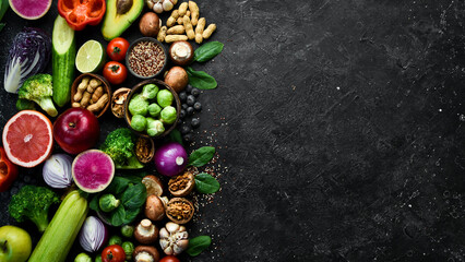 Big set of organic food. On a black chalkboard. Fresh raw fruits, vegetables, nuts, mushrooms and berries. On a black stone background. Top view. Copy space.