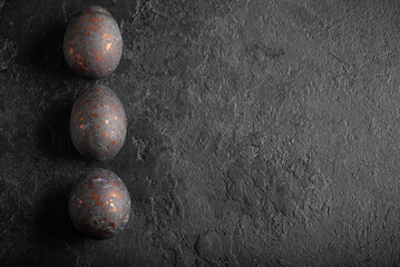 Easter hibiscus tea-dyed chicken eggs on a black grunge background. Copy space. Top view