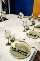 glass and a plate with a flower, table setting for dinner with the whole family in the interior of the house.