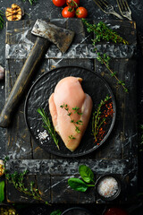 Chicken meat. Raw fresh chicken breast on a plate. Top view. On a black stone background.