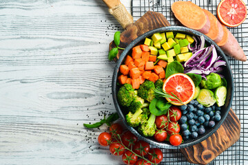 Vegan Buddha Bowl: Sweet Potatoes, Blueberries, Avocados, Cabbage and Orange. Dietary food. Top view. Free space for your text.