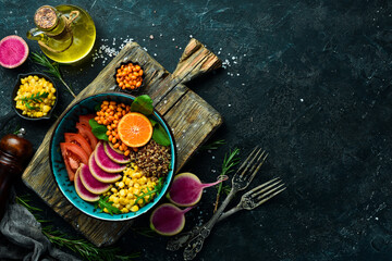 Buddha bowl: quinoa, spinach, corn, tomatoes and watermelon radish, sea buckthorn. Healthy vegetarian eating, super food. Top view On a stone background.