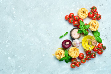 Preparation of pasta. Dry pasta and ingredients: tomatoes, basil, pepper and rosemary, on a gray stone background. Dry pasta. Top view. Free space for text.