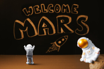 Figures of astronauts on the background of a chalky black board with the inscription welcome to...