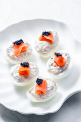 boiled eggs filled with tuna fish spread and smoked salmon and  black caviar on the top