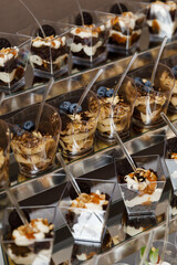 A lot of glasses with dessert in row decorated with whipped cream and cocoa, isolated on table.
