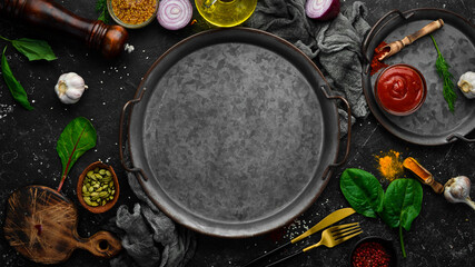 Black stone cooking background. Spices and vegetables. Top view. Free space for your text.