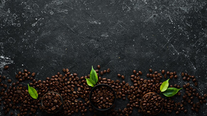 Fragrant roasted coffee beans on a black stone background. Top view. Free space for text.