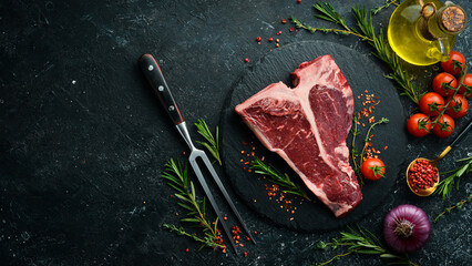 Raw T-bone steak on a stone table with thyme, rosemary and spices. Top view. Flat lay top view on...