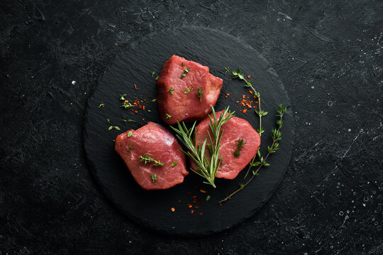 Meat. Raw pork tenderloin with spices on a black stone background. Top view. Rustic style.