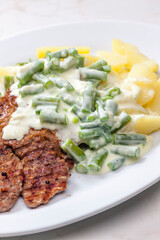 pork meat with cream sauce of green beans and cooked potatoes