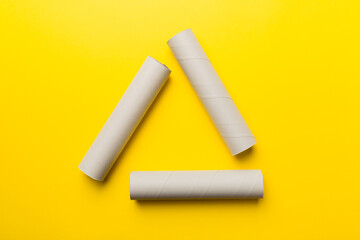 Empty toilet paper roll on colored background. Recyclable paper tube with metal plug end made of kraft paper or cardboard in the form of a recycling sign