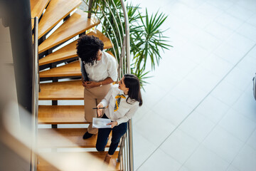 Top view of two businesswomen, standing on the stairs, discussin