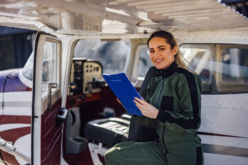 Naklejka premium Portrait of lovely caucasian aircraft mechanic, inspecting the plane.
