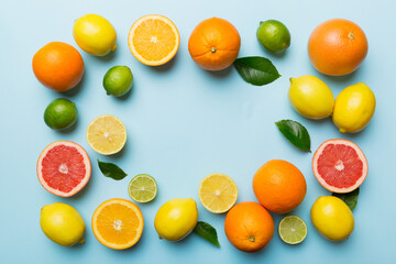 Flat lay of citrus fruits like lime, orange and lemon with lemon tree leaves on light colored background making a frame. Space for text healthy concept