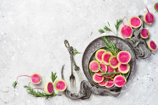 Slices of pink watermelon radish on a plate. Dietary useful vegetables. On a gray stone background.